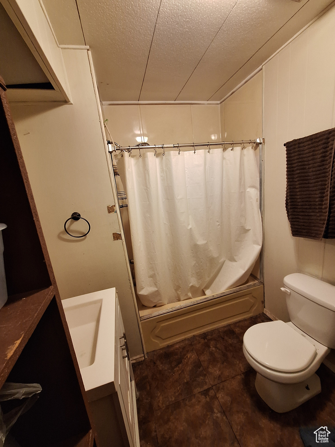 Full bathroom featuring a textured ceiling, vanity, toilet, and shower / bath combo with shower curtain