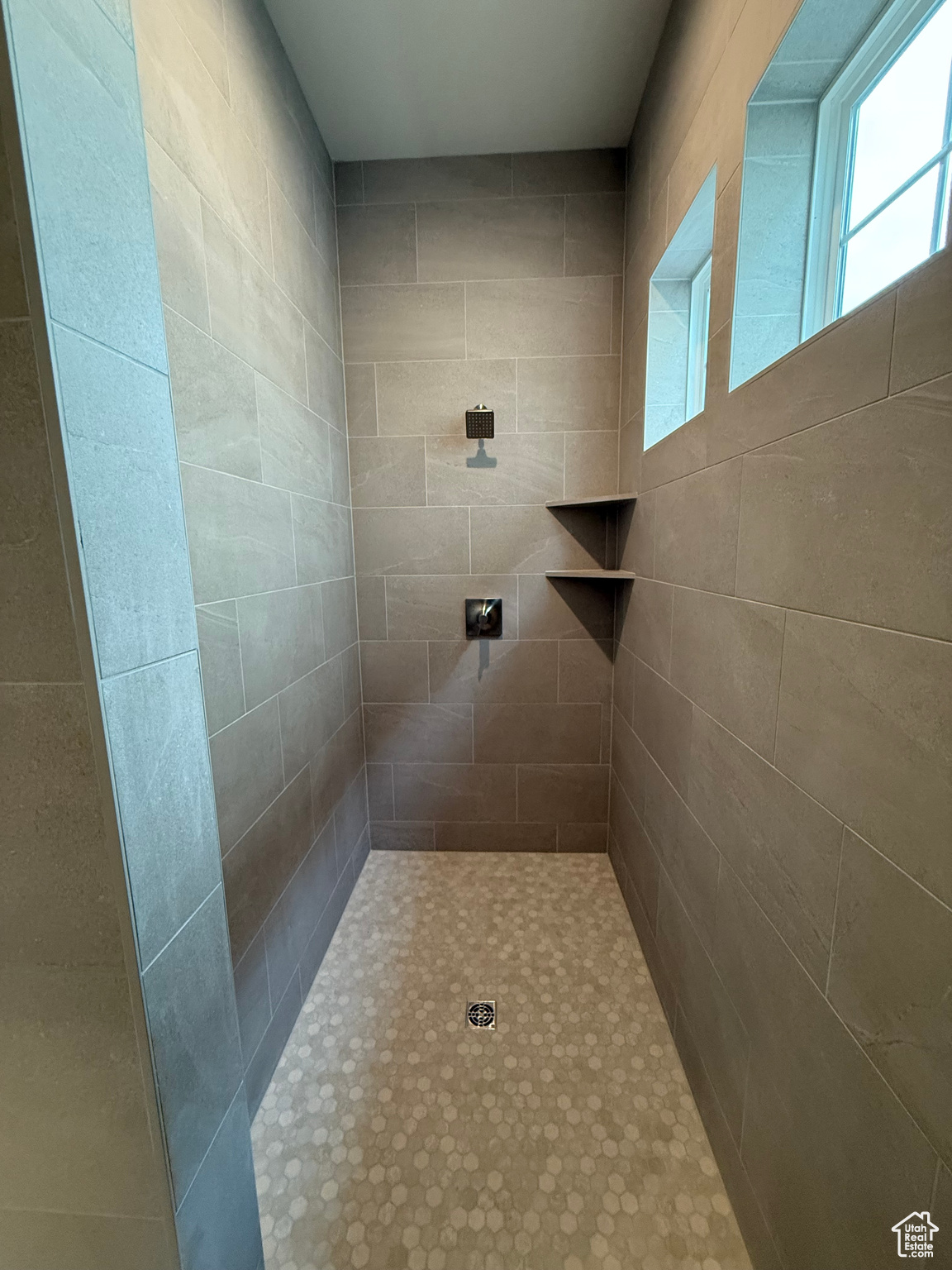 Walk in shower sequestered from rest of bathroom by wall (left).