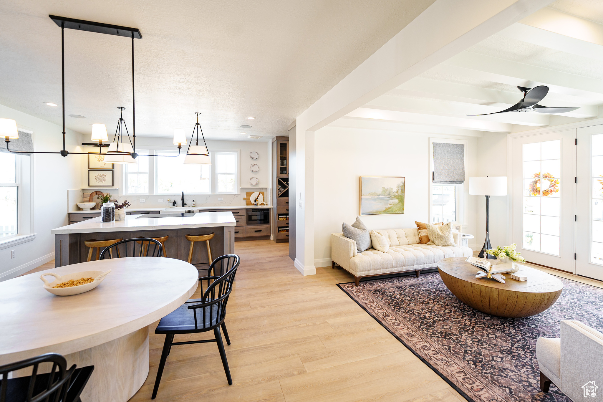 Interior space featuring sink, a healthy amount of sunlight, ceiling fan with notable chandelier, and light hardwood / wood-style flooring