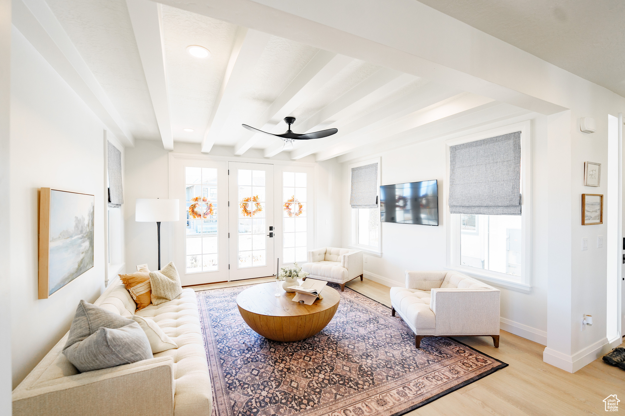 Living room featuring beamed ceiling, light hardwood / wood-style floors, and ceiling fan