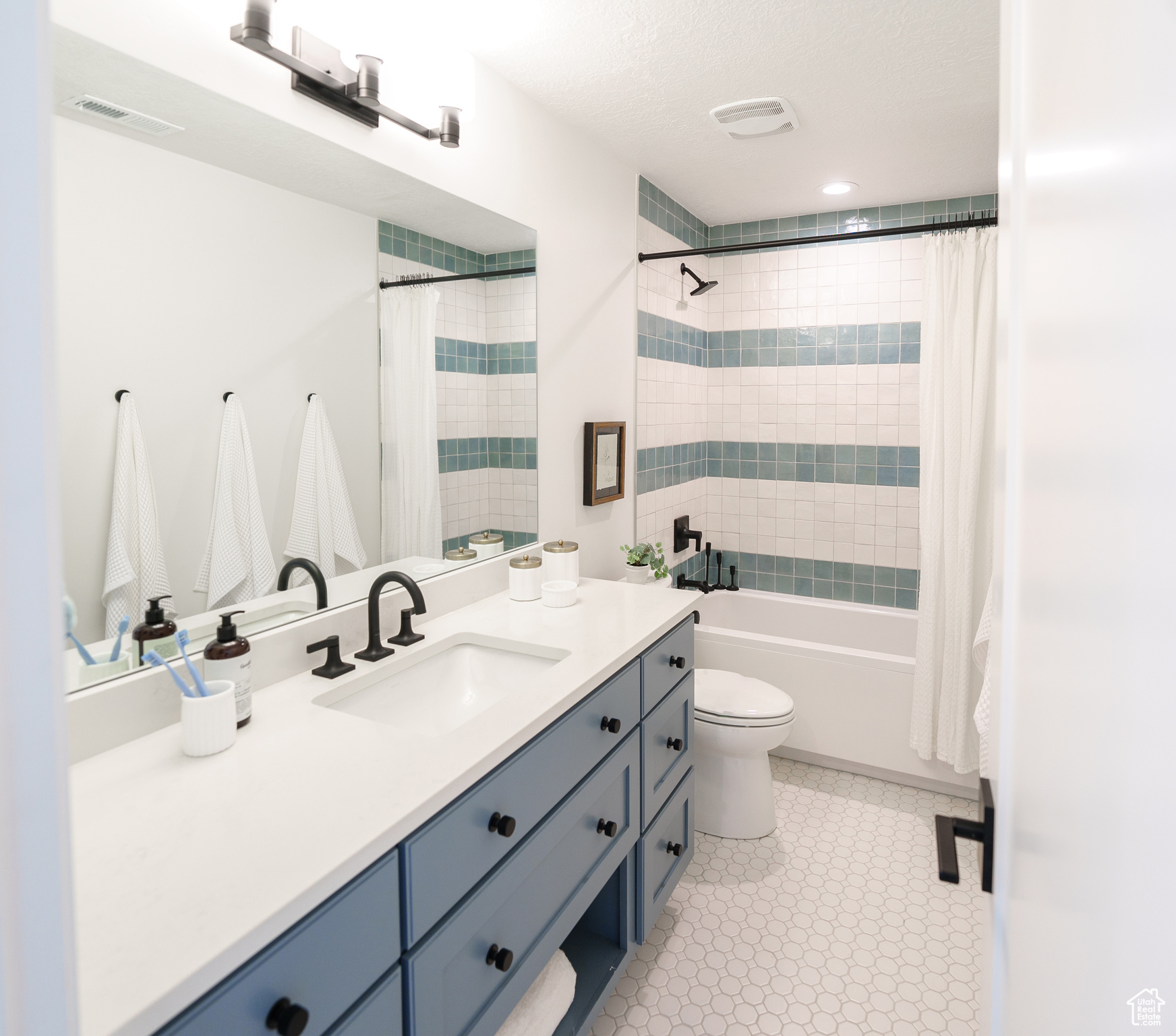 Full bathroom featuring vanity, toilet, a textured ceiling, and shower / tub combo with curtain