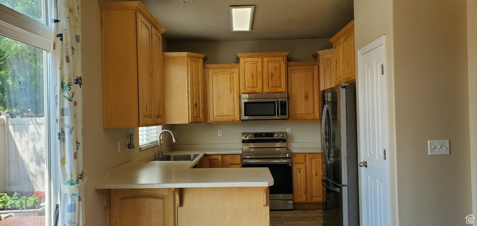 Kitchen with kitchen peninsula, sink, stainless steel appliances, and wood-type flooring