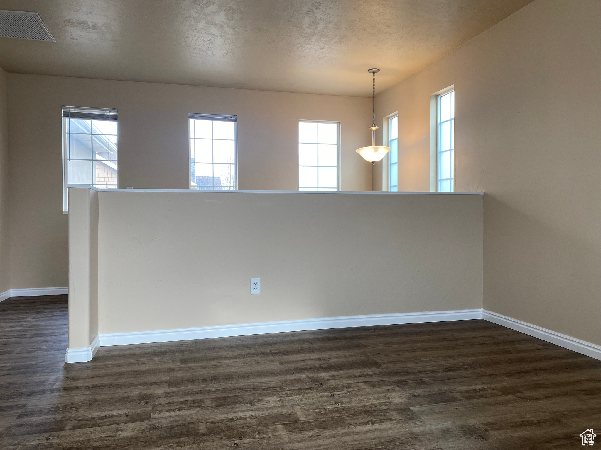 Empty room featuring dark hardwood / wood-style floors and a wealth of natural light