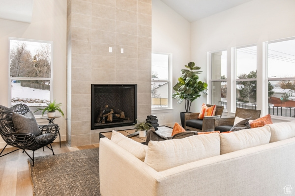 Living room featuring a tile fireplace, light wood-type flooring, and high vaulted ceiling