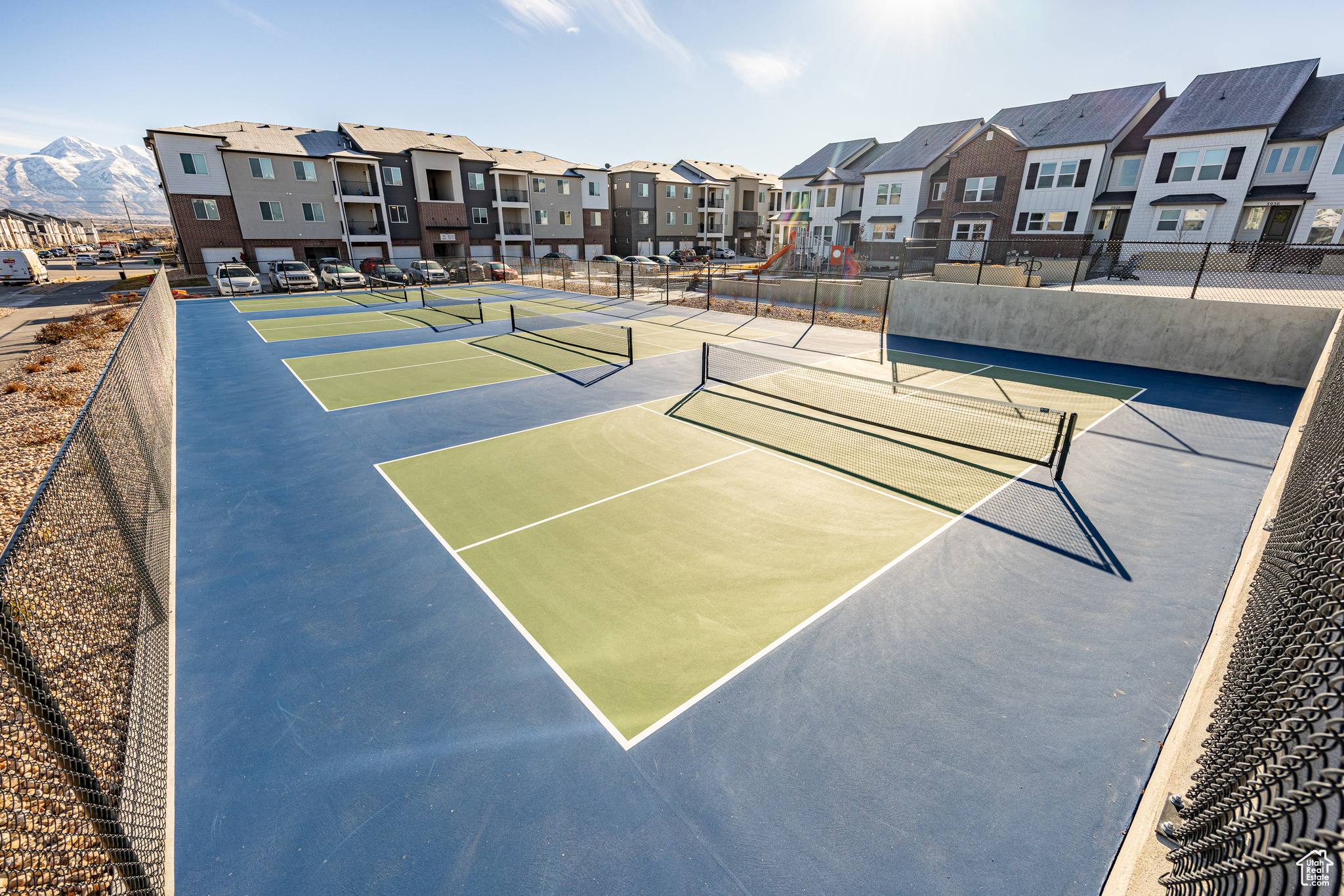 View of tennis court with basketball hoop and a mountain view