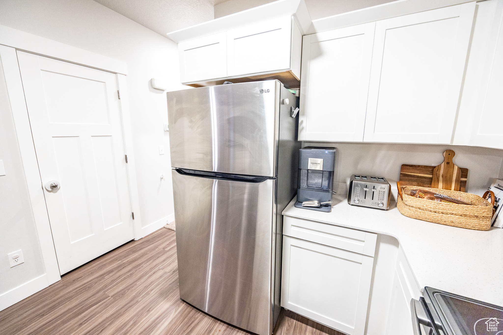 Kitchen featuring white cabinets, light hardwood / wood-style floors, and stainless steel refrigerator