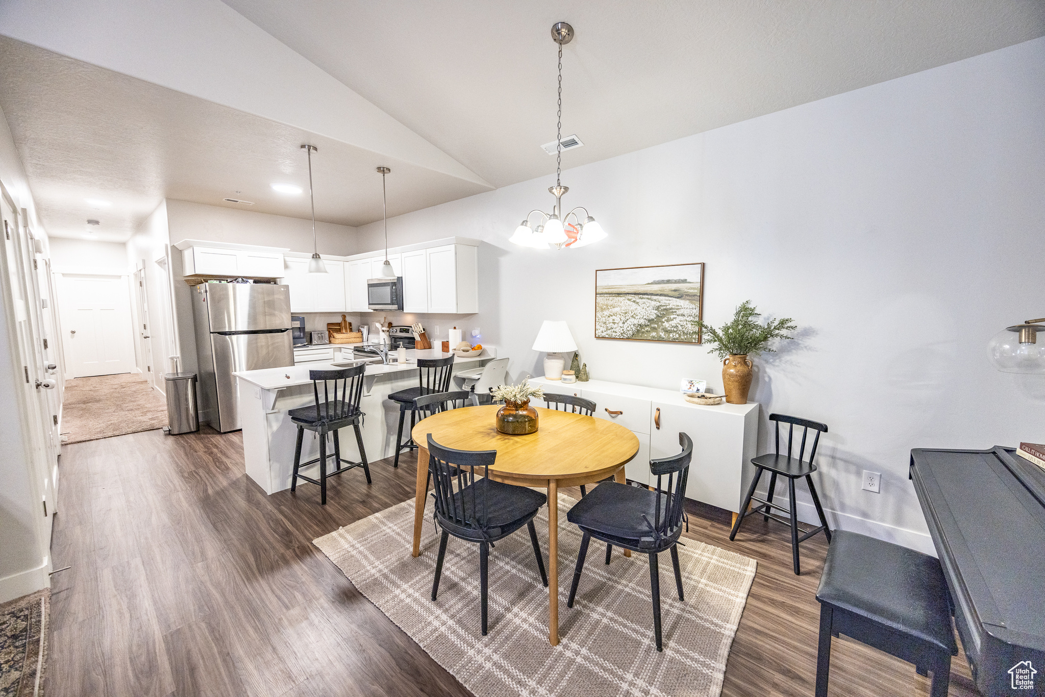 Dining area featuring dark hardwood / wood-style floors, a chandelier, and lofted ceiling