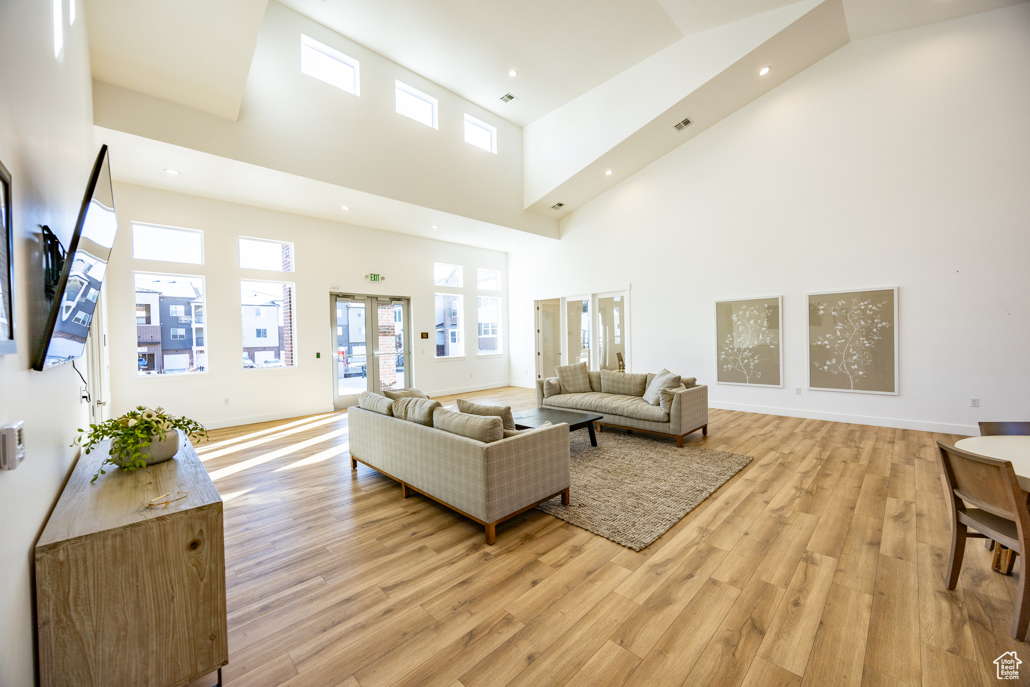 Living room featuring french doors, light hardwood / wood-style flooring, and a high ceiling