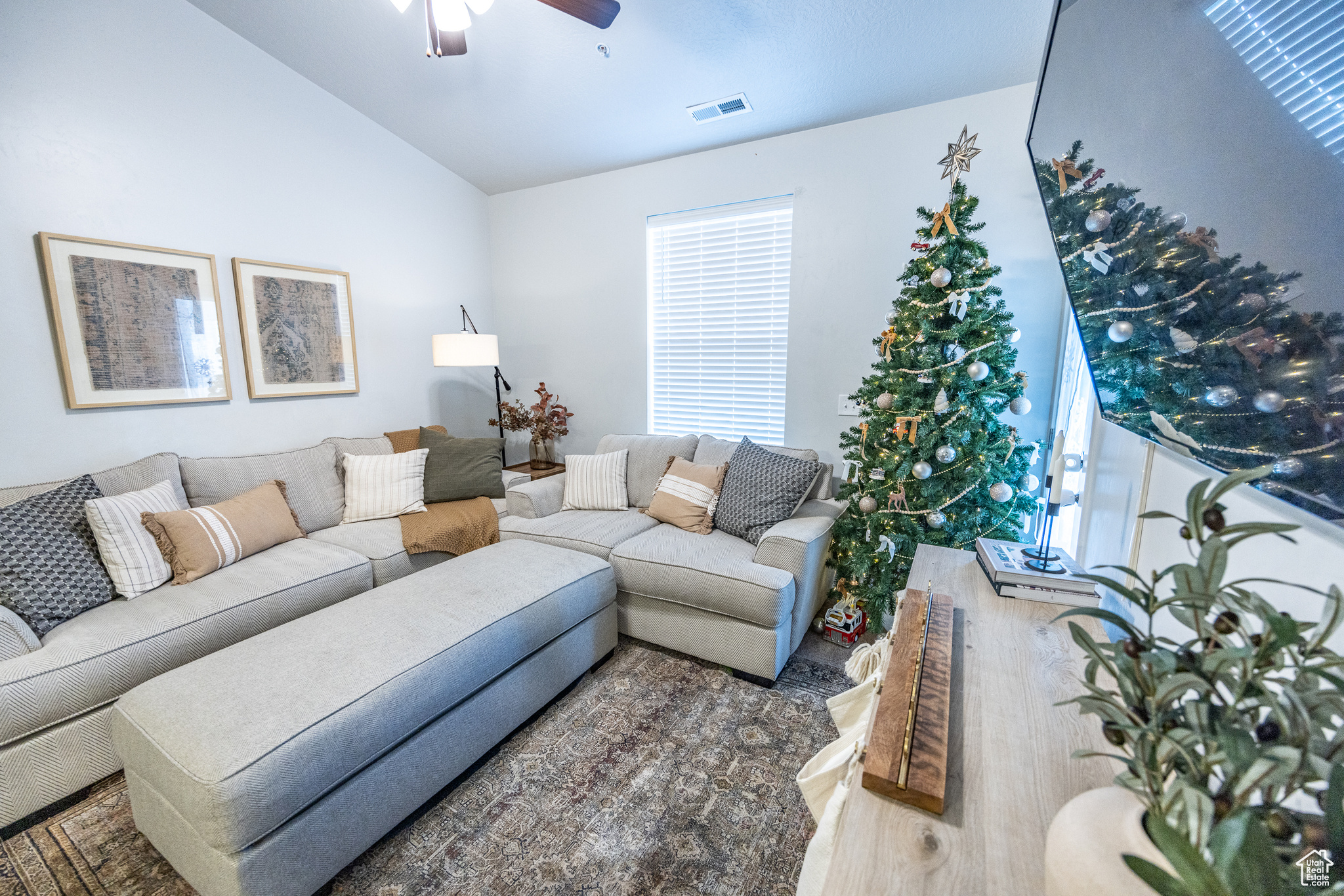 Living room featuring wood-type flooring, vaulted ceiling, and ceiling fan