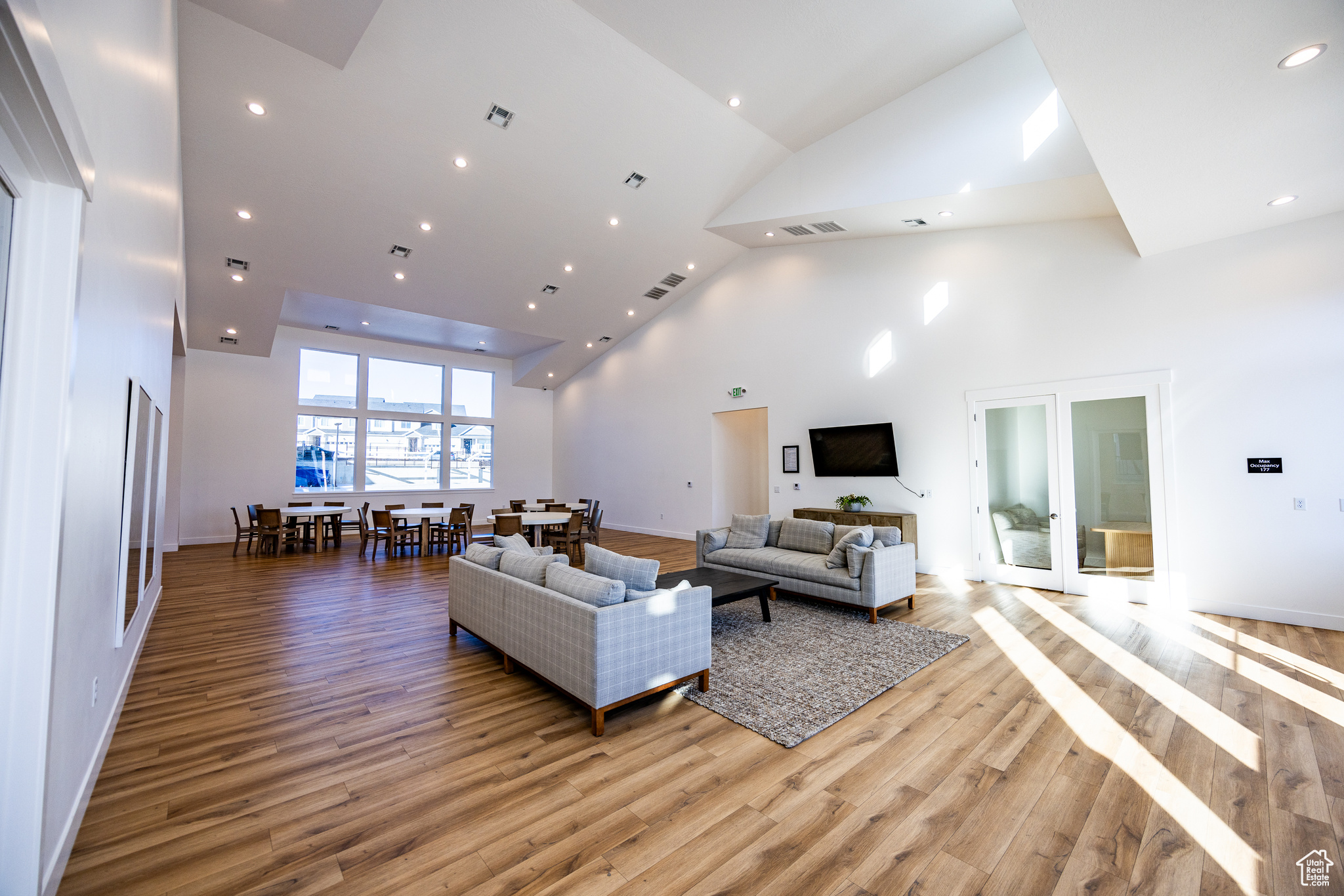 Living room with french doors, light hardwood / wood-style floors, and a high ceiling