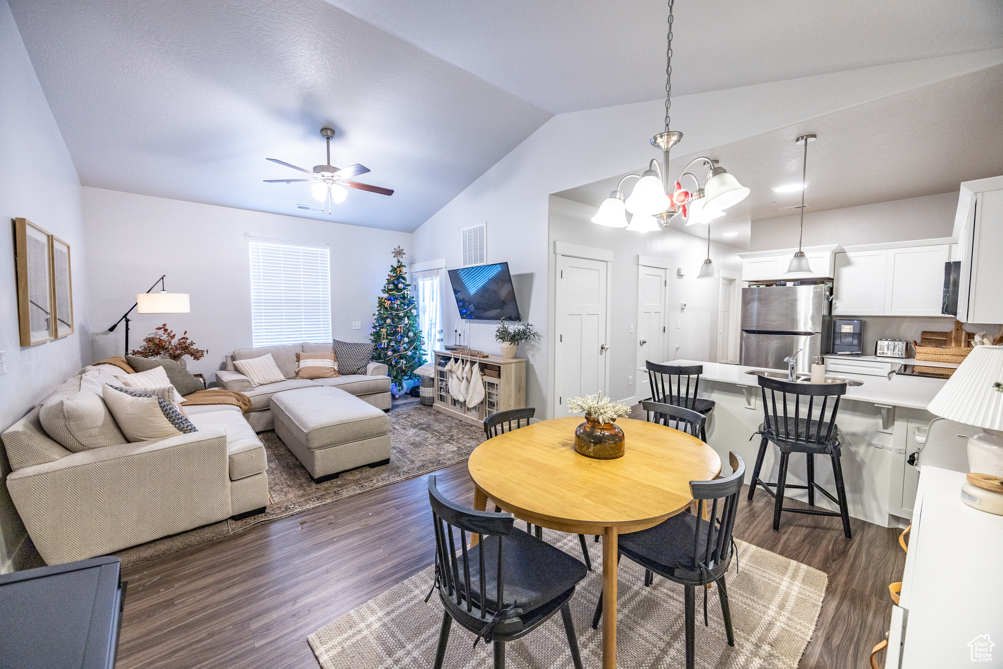 Dining space featuring dark hardwood / wood-style flooring, ceiling fan with notable chandelier, and lofted ceiling