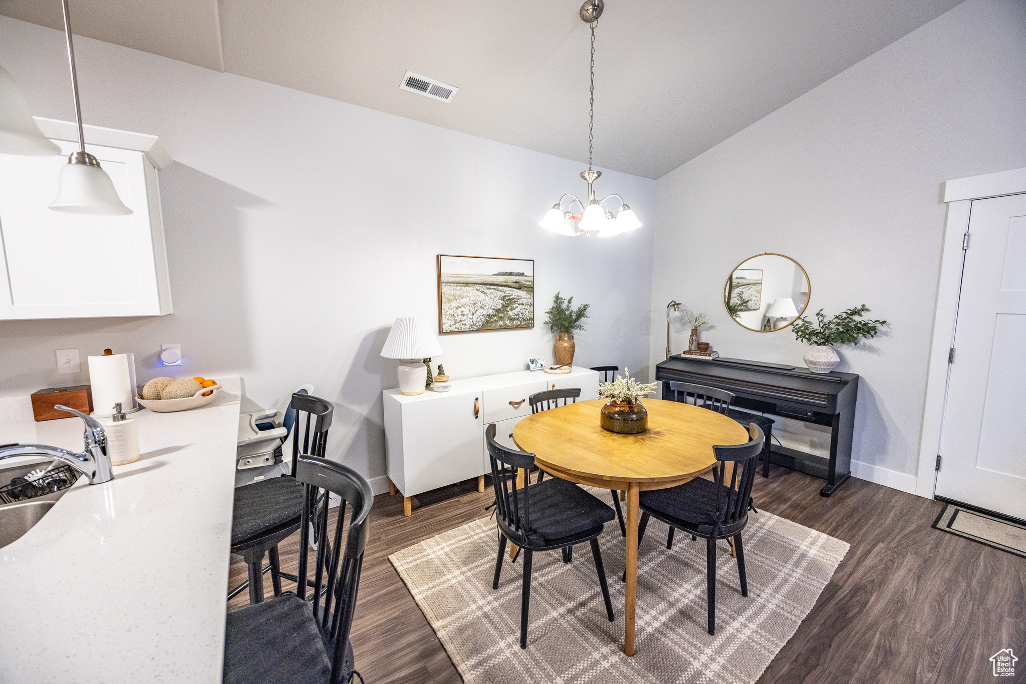 Dining room featuring sink, dark wood-type flooring, and a notable chandelier