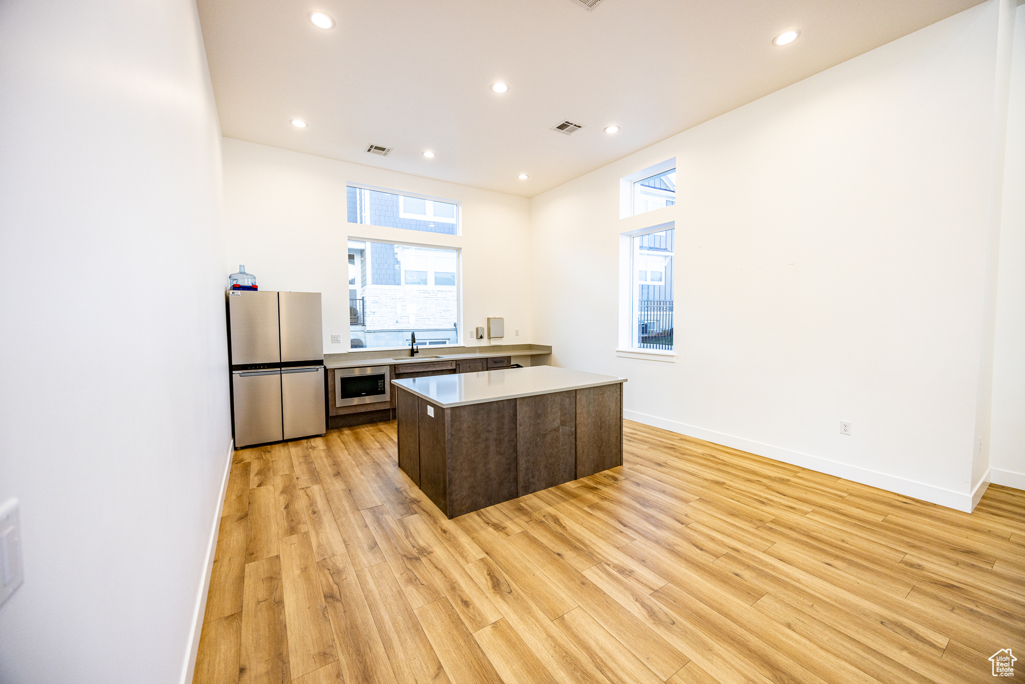 Kitchen featuring light wood-type flooring, a center island, stainless steel appliances, and a healthy amount of sunlight