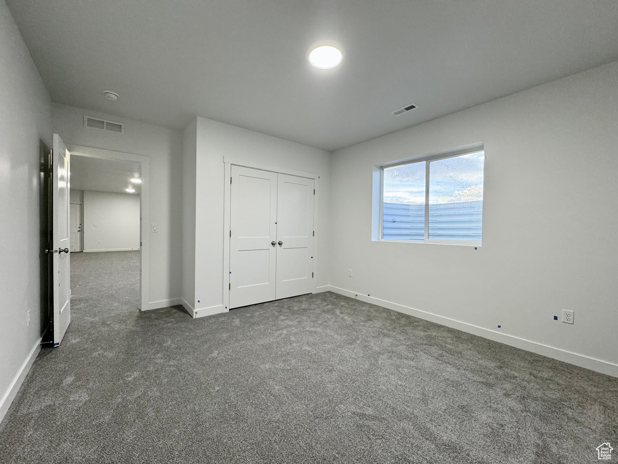 Unfurnished bedroom featuring dark colored carpet and a closet