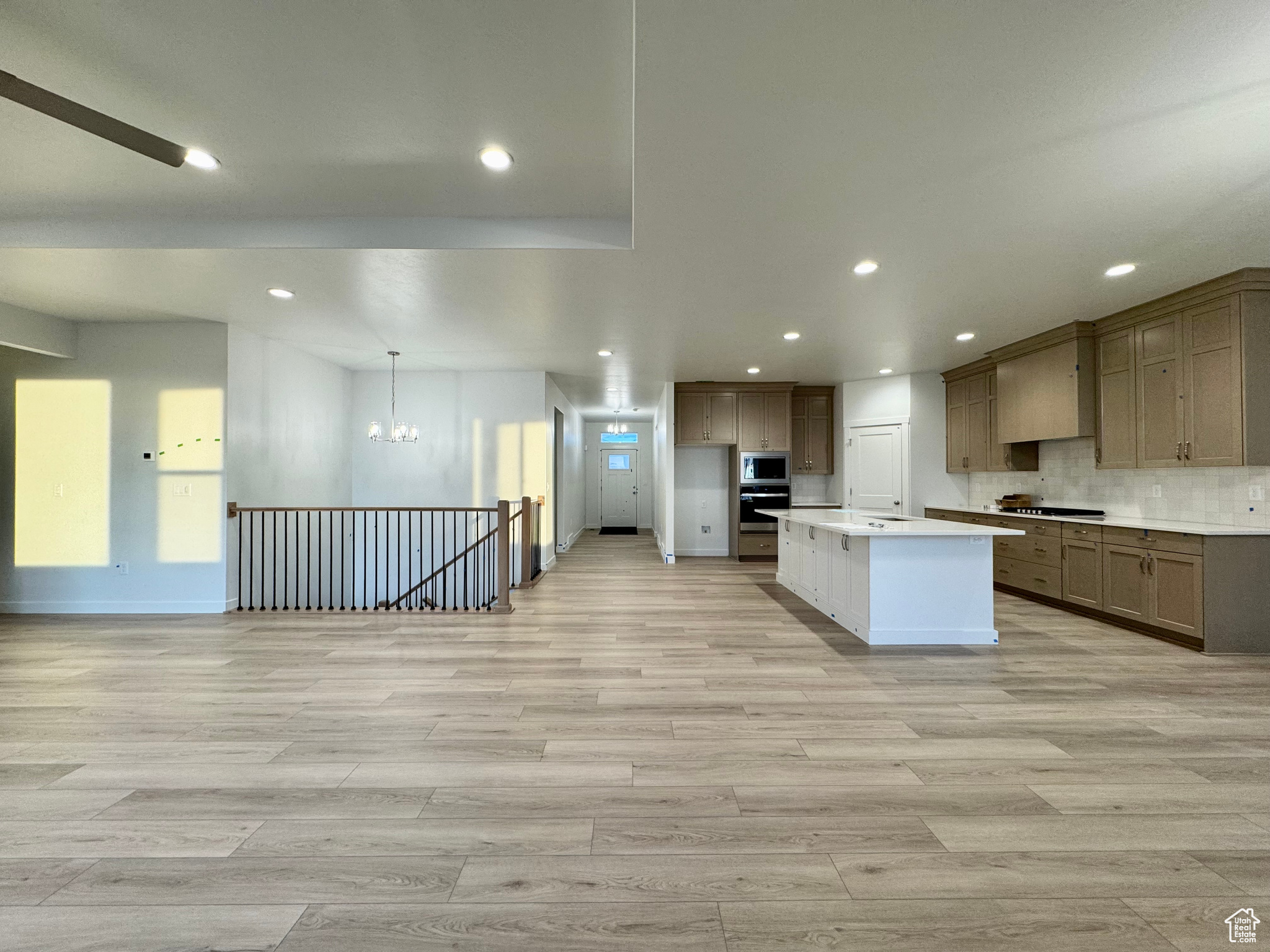 Kitchen with appliances with stainless steel finishes, a center island, decorative light fixtures, and light hardwood / wood-style floors