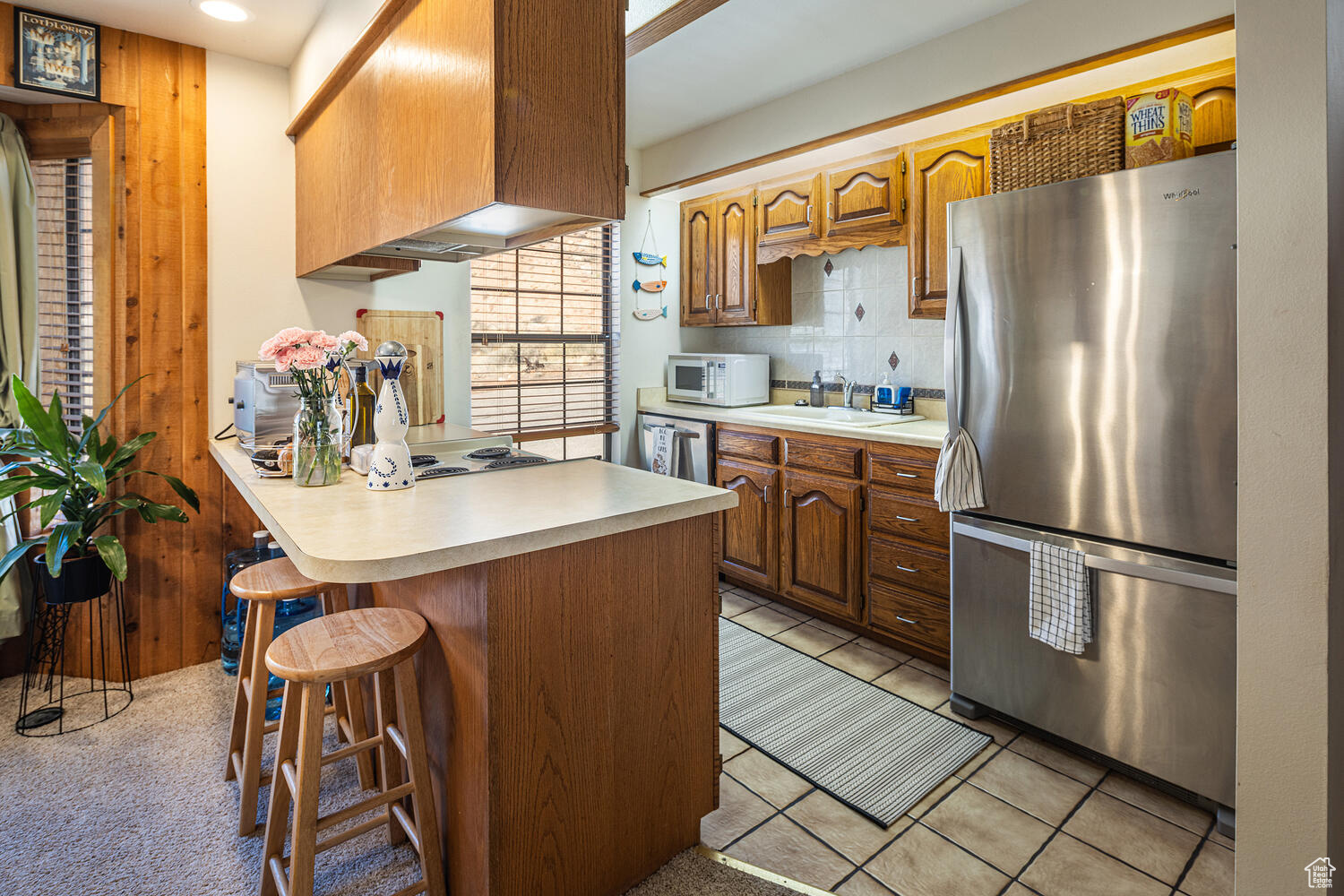 Kitchen featuring sink, stainless steel appliances, premium range hood, kitchen peninsula, and a kitchen bar