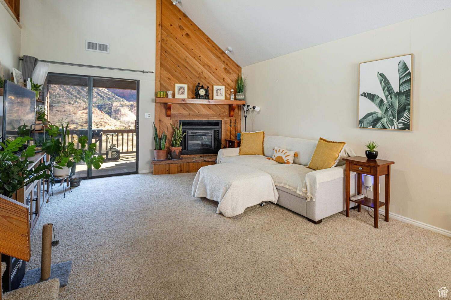 Carpeted living room with high vaulted ceiling and wood walls