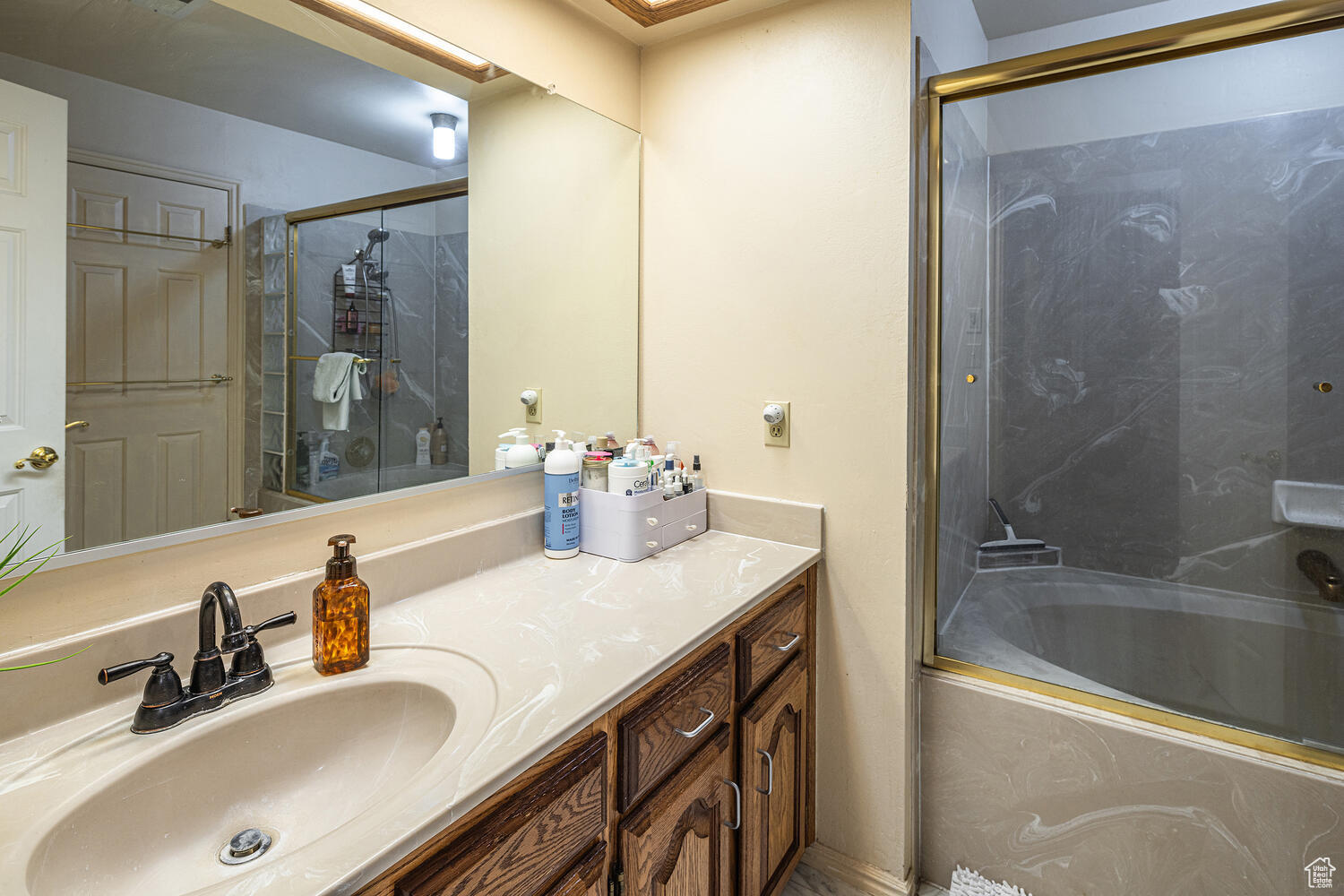 Bathroom with vanity and bath / shower combo with glass door