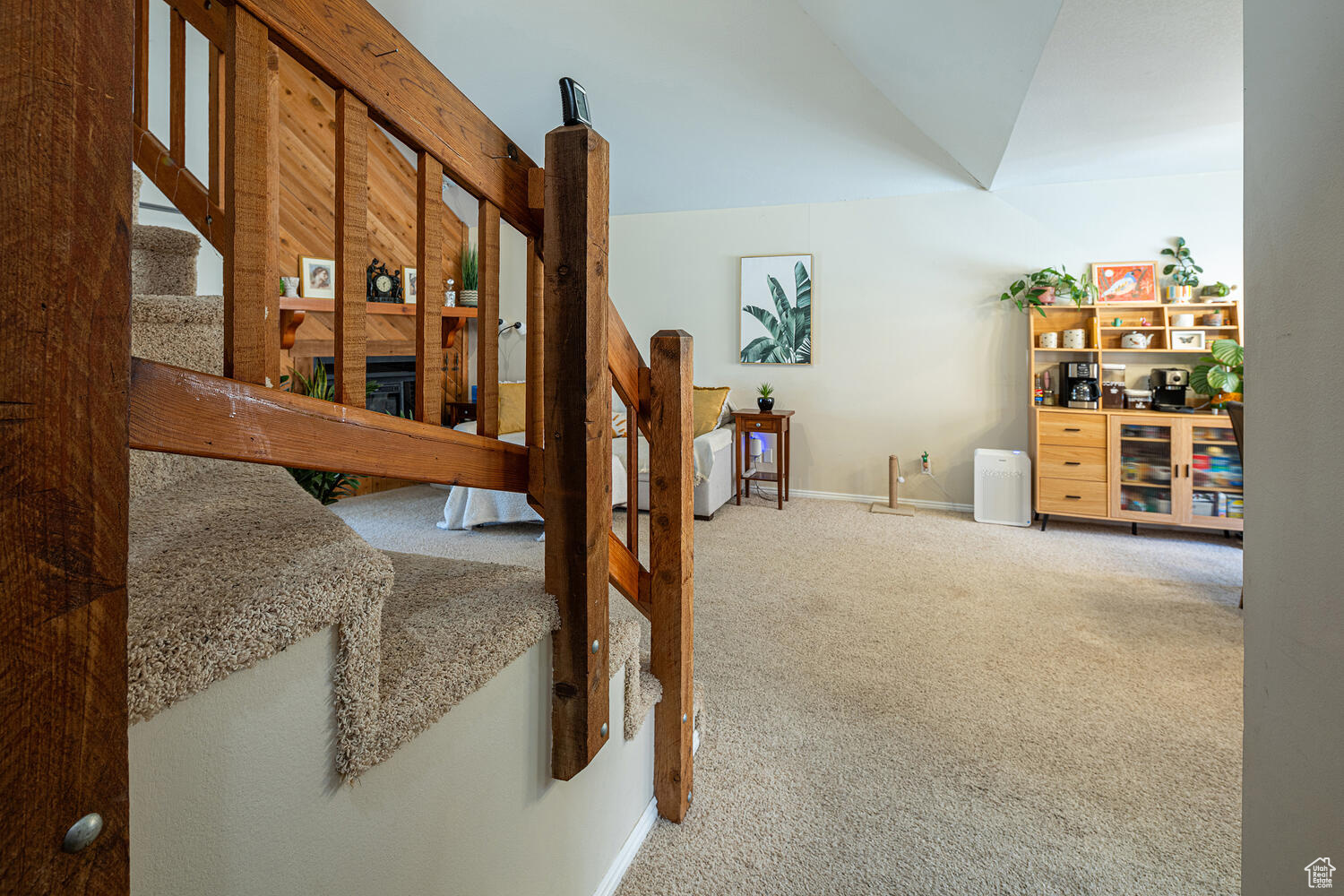 Staircase with a fireplace, carpet, and vaulted ceiling