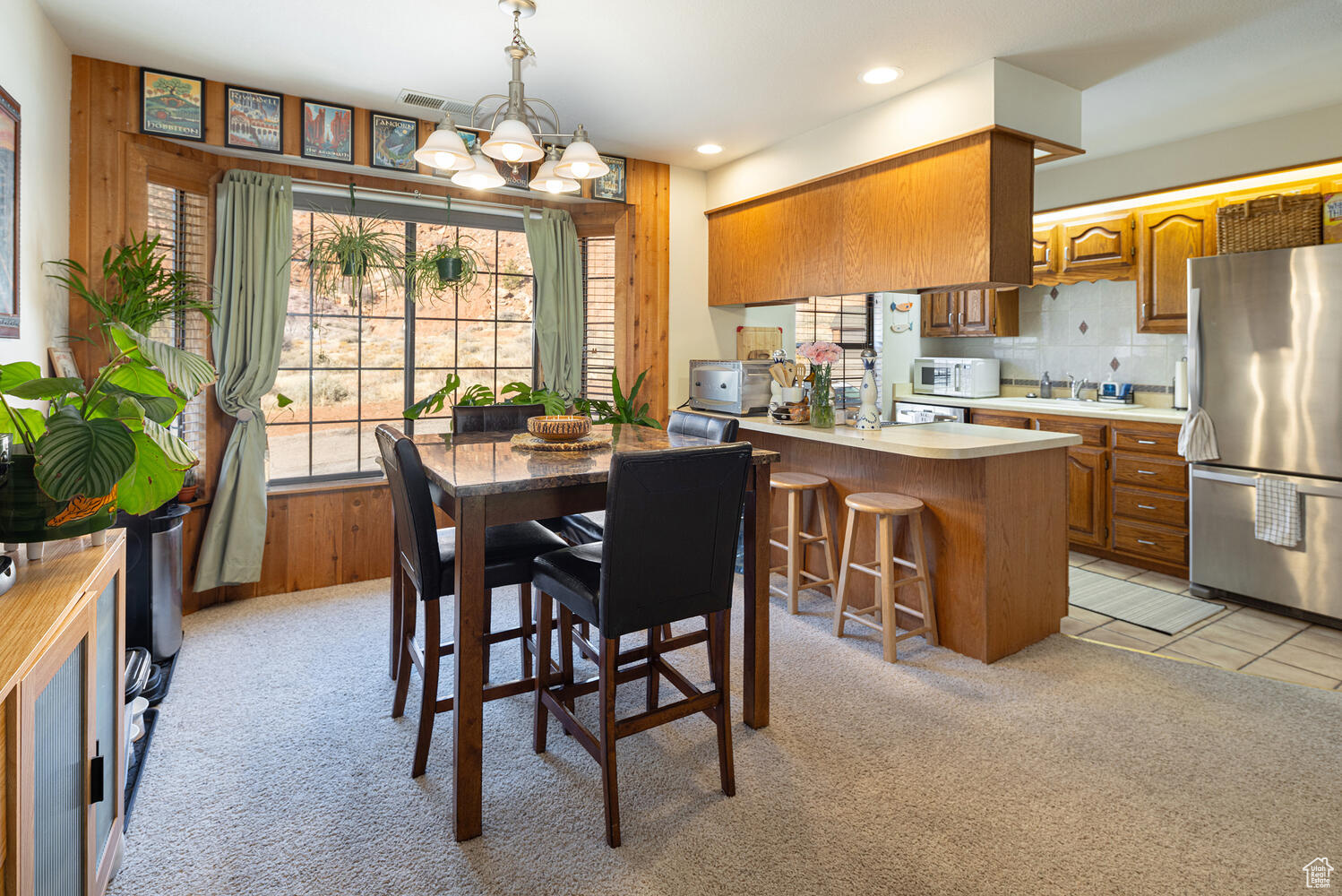 Carpeted dining area featuring wooden walls and an inviting chandelier