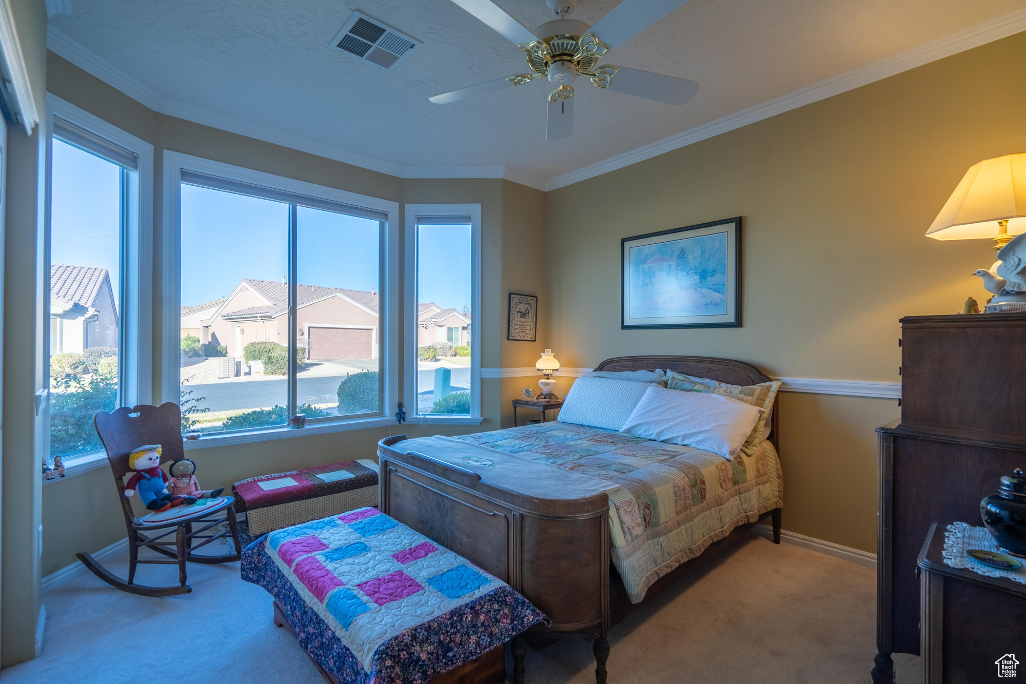 Carpeted 2nd  bedroom featuring ceiling fan, ornamental molding, & bay window