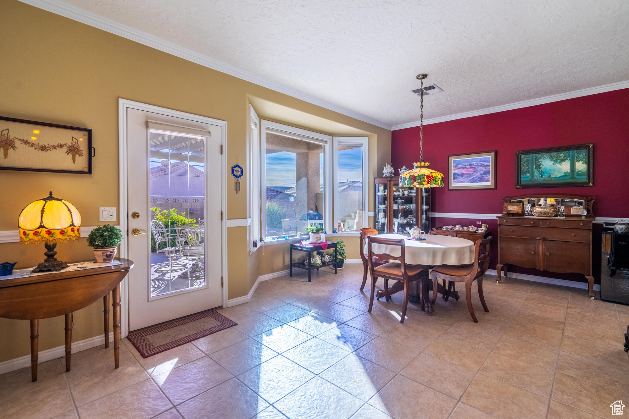 Dining space featuring light tile patterned flooring, a textured ceiling, and ornamental molding