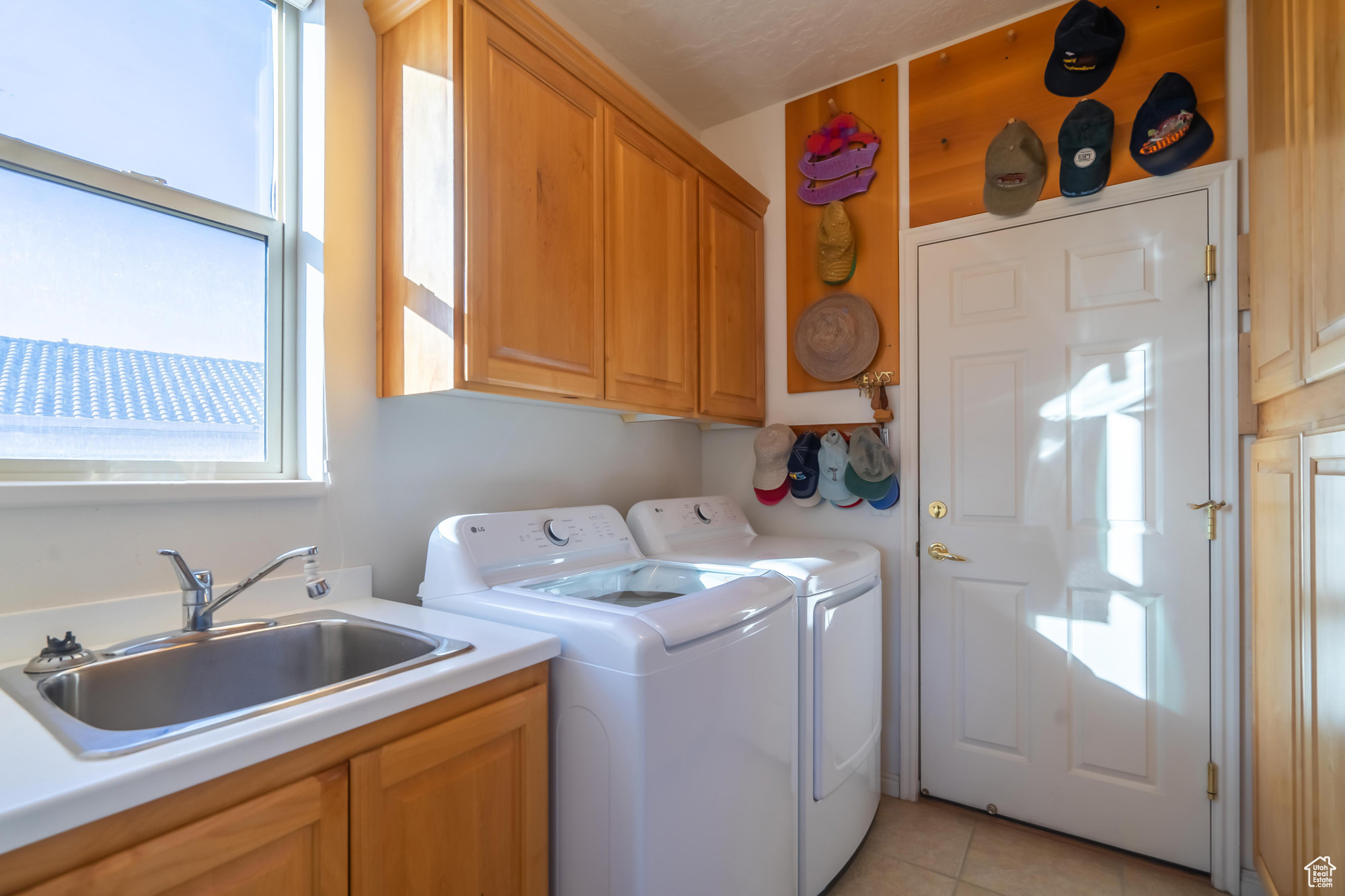 Laundry area with separate washer and dryer, sink, light tile patterned floors, and cabinets