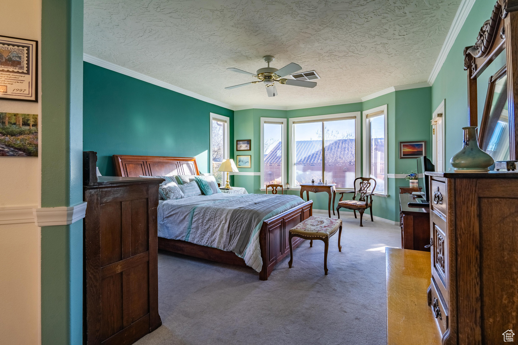 Carpeted primary bedroom with ceiling fan, crown molding, and a textured ceiling