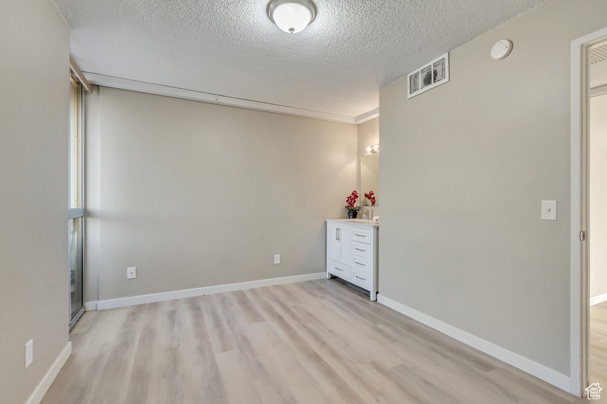 Unfurnished room with a textured ceiling and light wood-type flooring