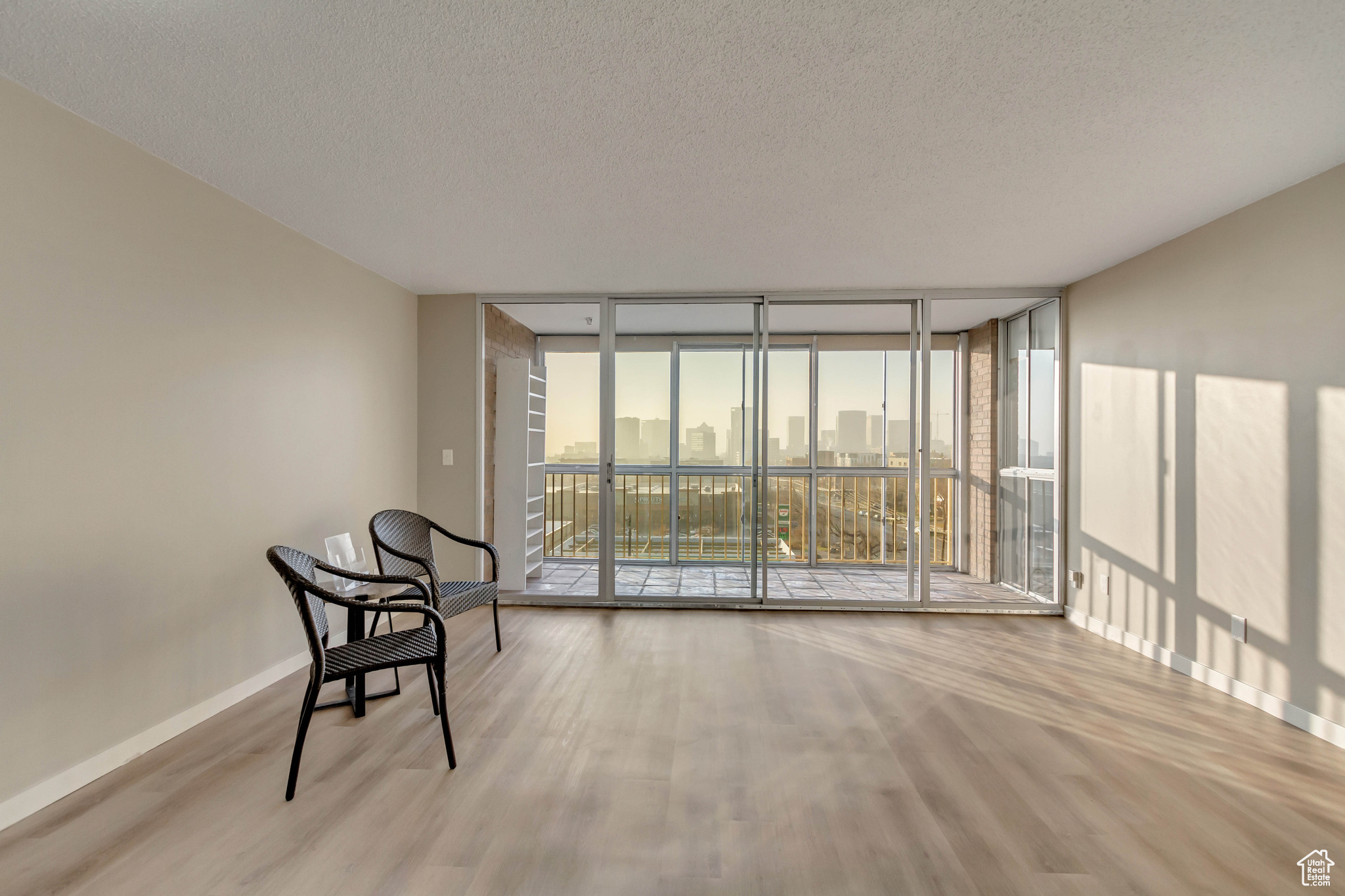 Sitting room with expansive windows, light hardwood / wood-style floors, and a textured ceiling