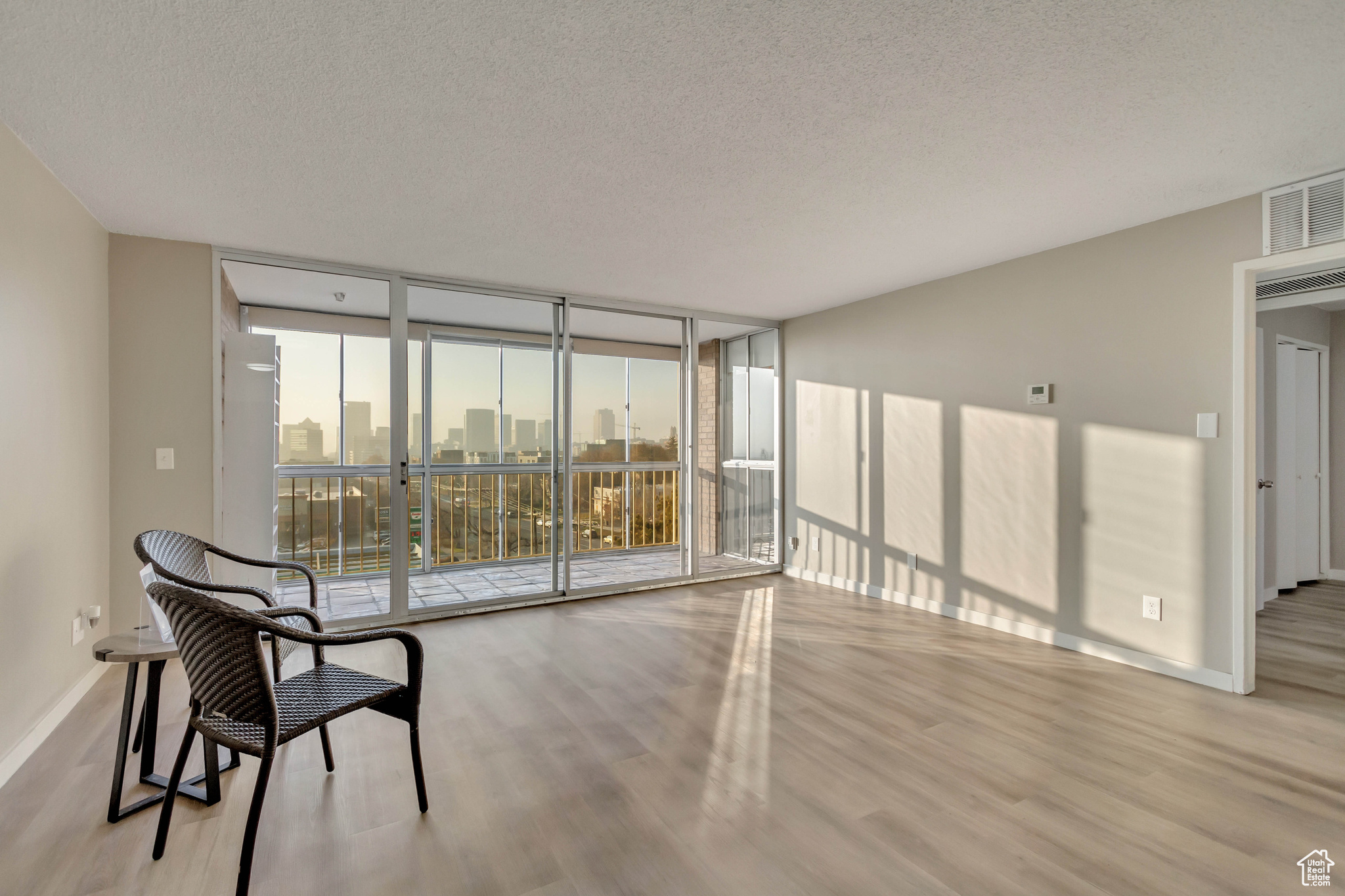 Empty room with floor to ceiling windows, light hardwood / wood-style floors, and a textured ceiling