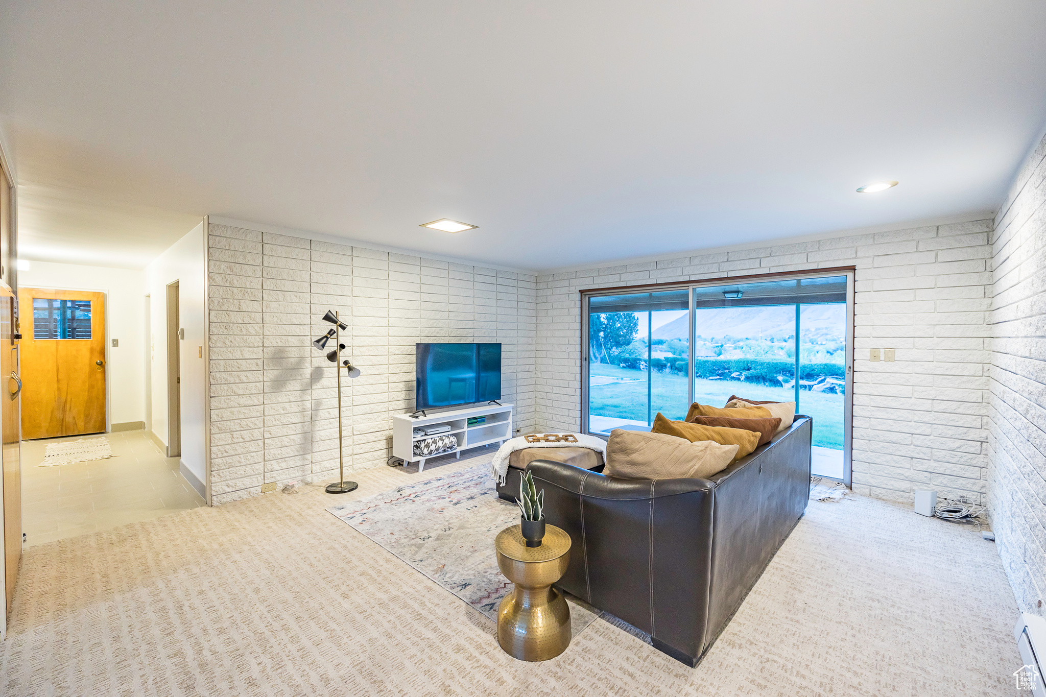 Living room featuring baseboard heating and brick wall