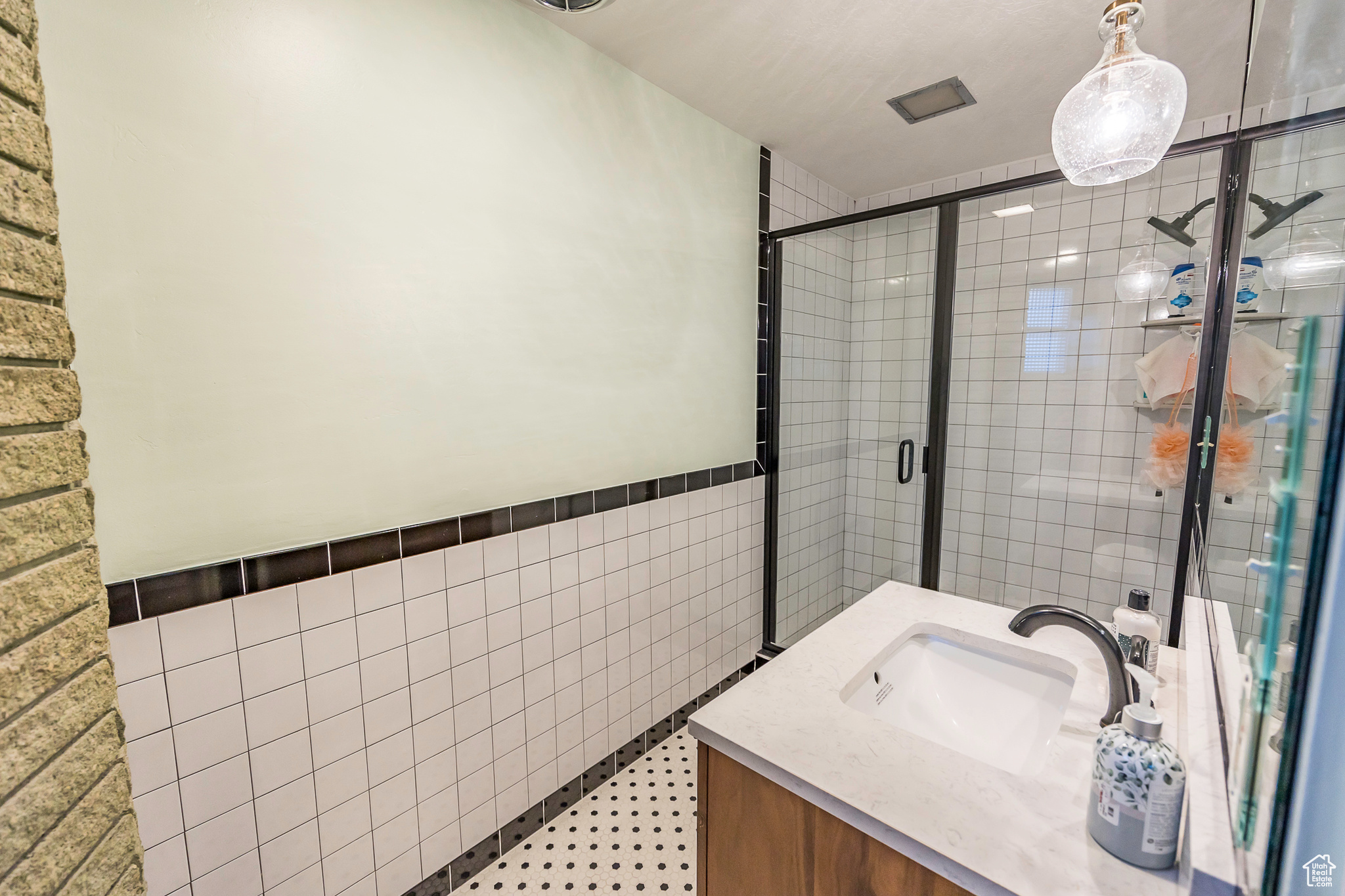 Bathroom featuring an enclosed shower, vanity, tile patterned floors, and tile walls