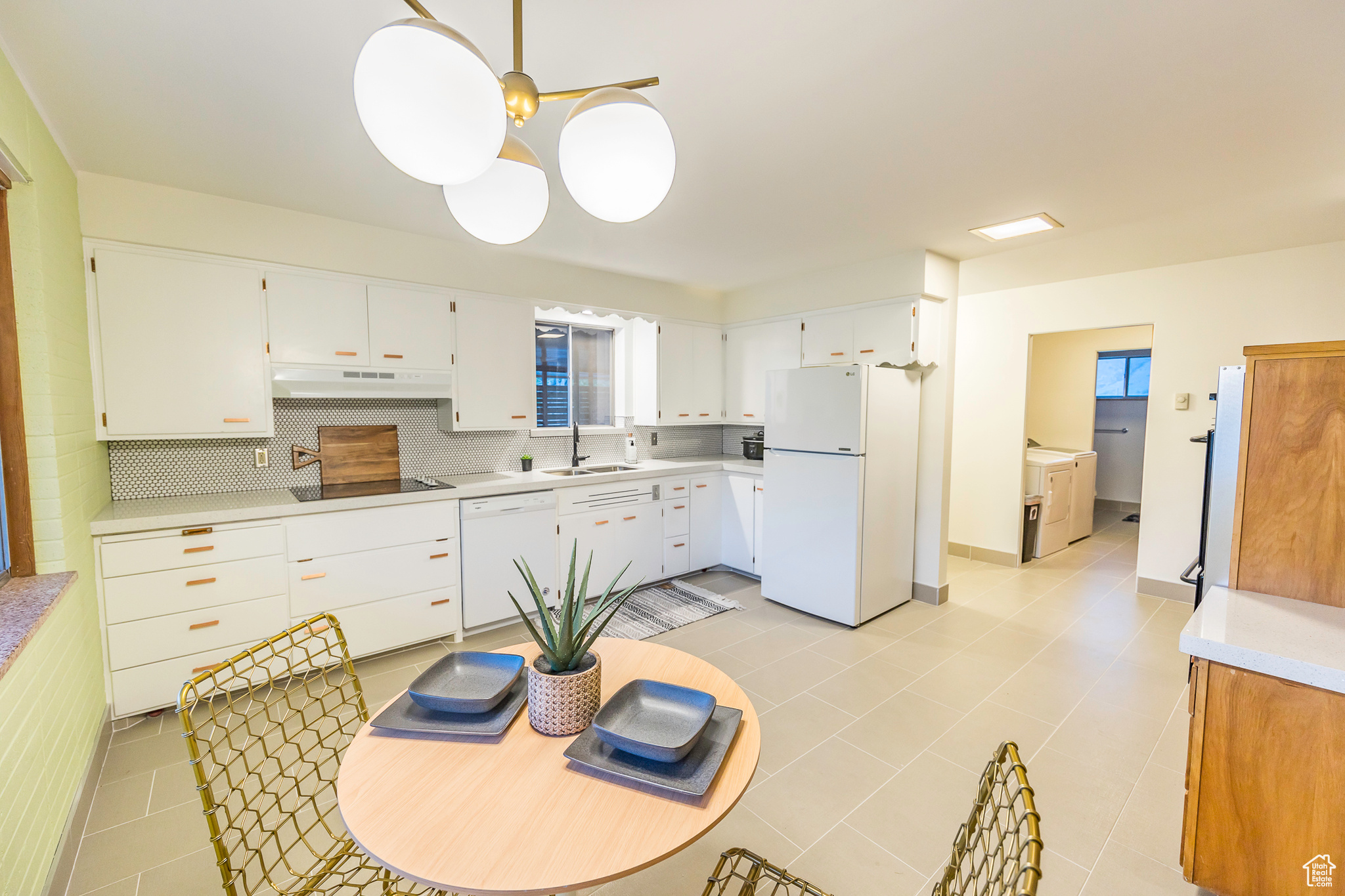 Kitchen featuring tasteful backsplash, white appliances, sink, light tile patterned floors, and white cabinets