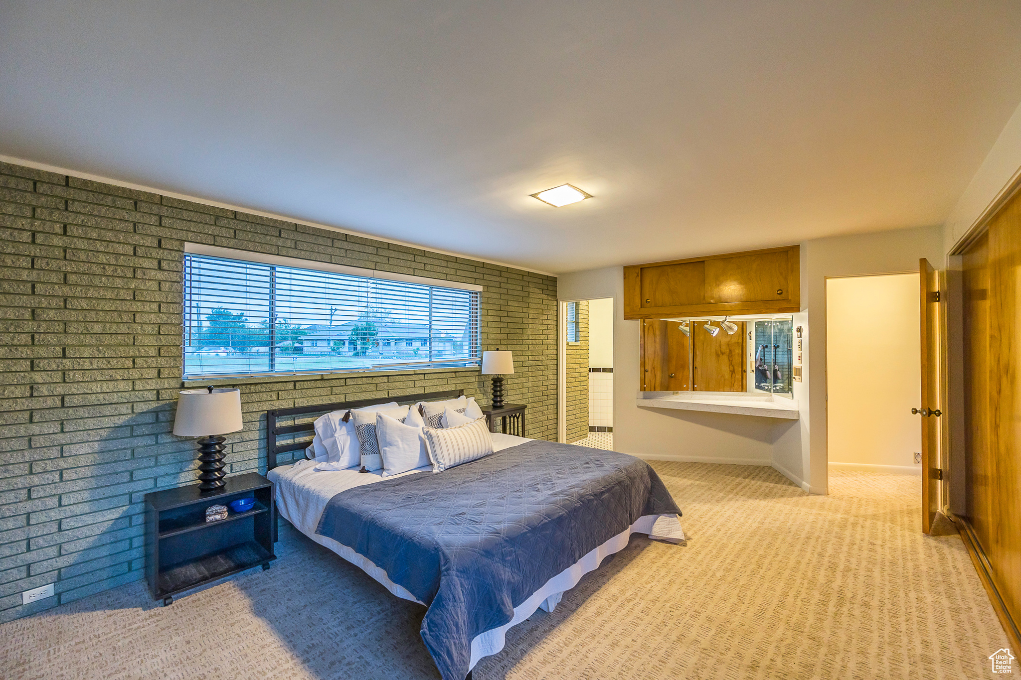 Carpeted bedroom featuring brick wall