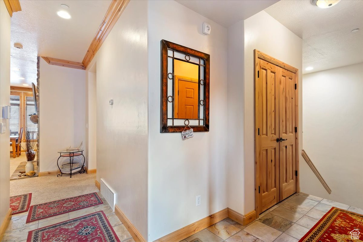 Hallway featuring light carpet and crown molding