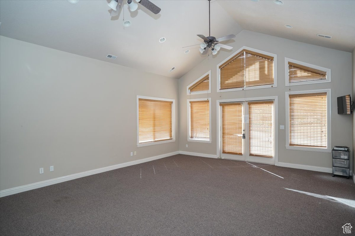 Club House Spare room with ceiling fan, dark carpet, and high vaulted ceiling