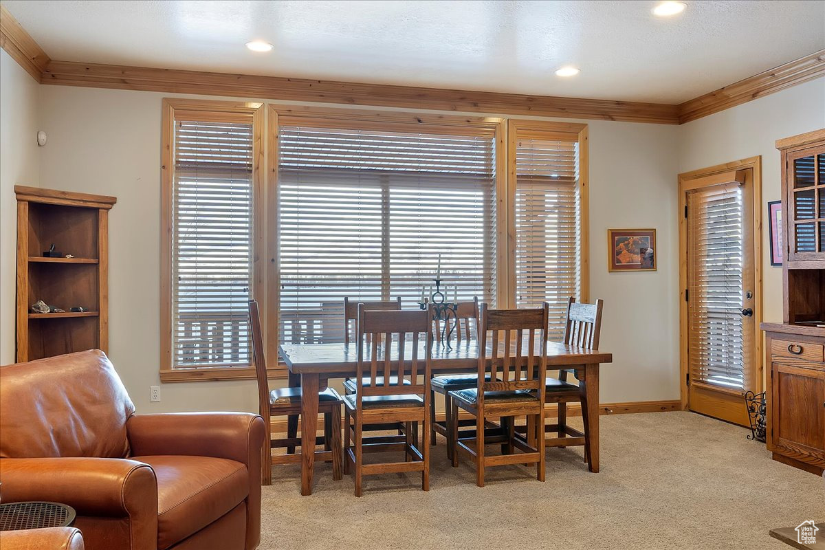 Carpeted dining room featuring ornamental molding