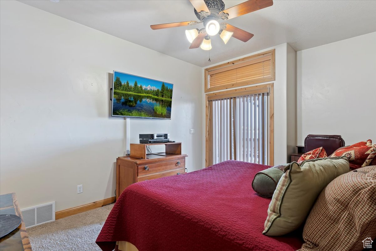 Large Basement bedroom with sliding glass doors to patio and lake. Carpeted bedroom with ceiling fan