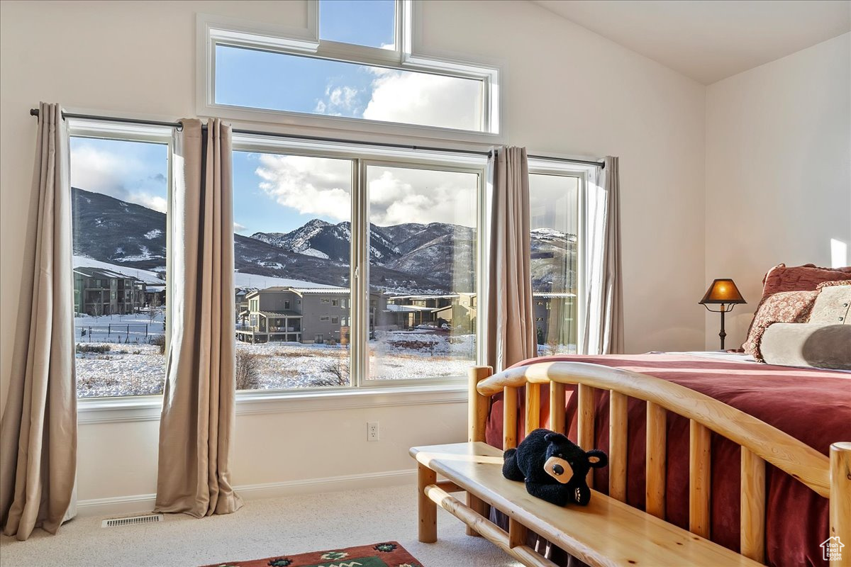 Carpeted bedroom featuring a mountain view, vaulted ceiling, and multiple windows