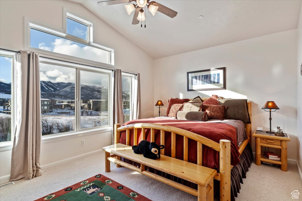 Carpeted bedroom with a mountain view, ceiling fan, and vaulted ceiling