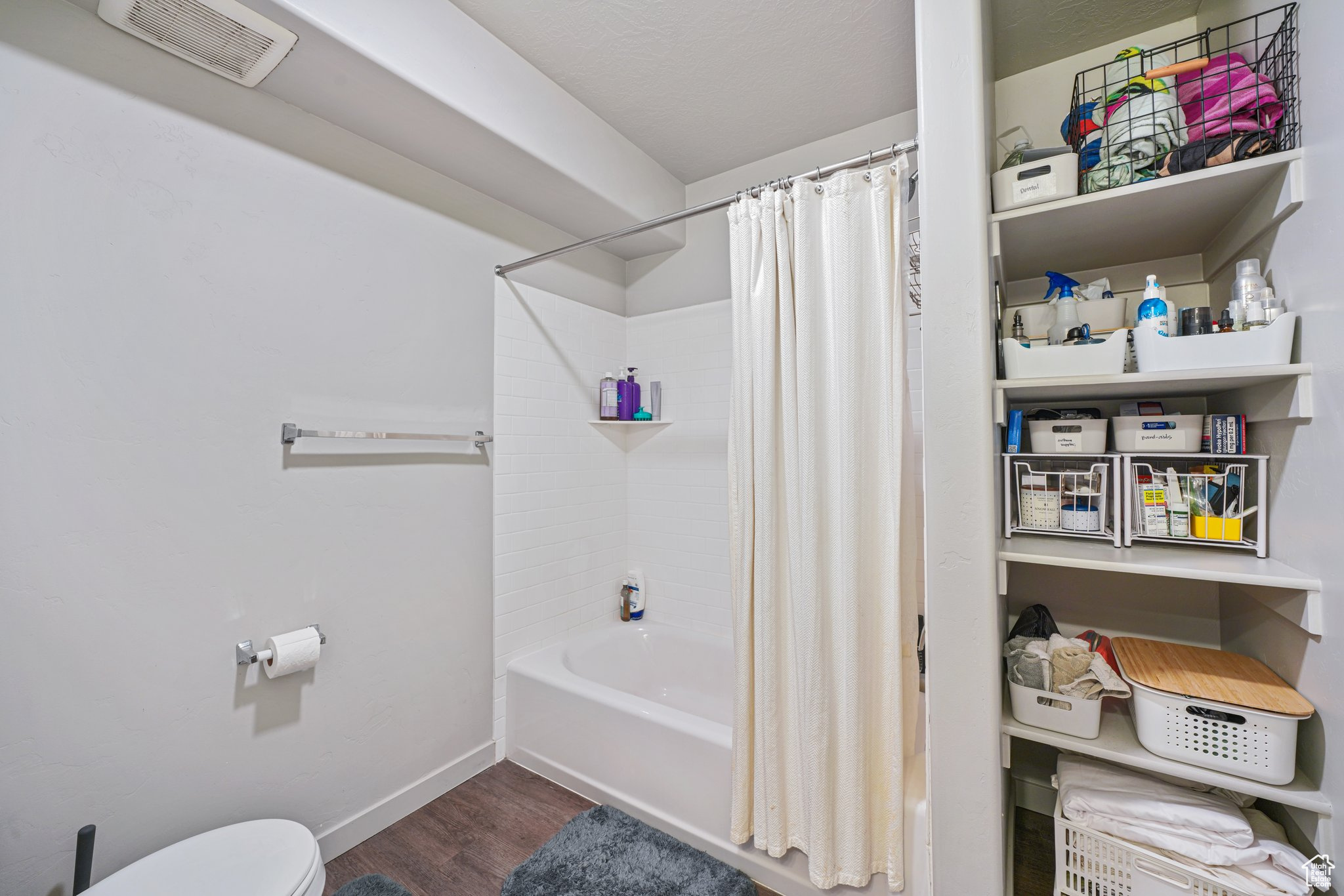 Bathroom with hardwood / wood-style floors, toilet, and shower / tub combo