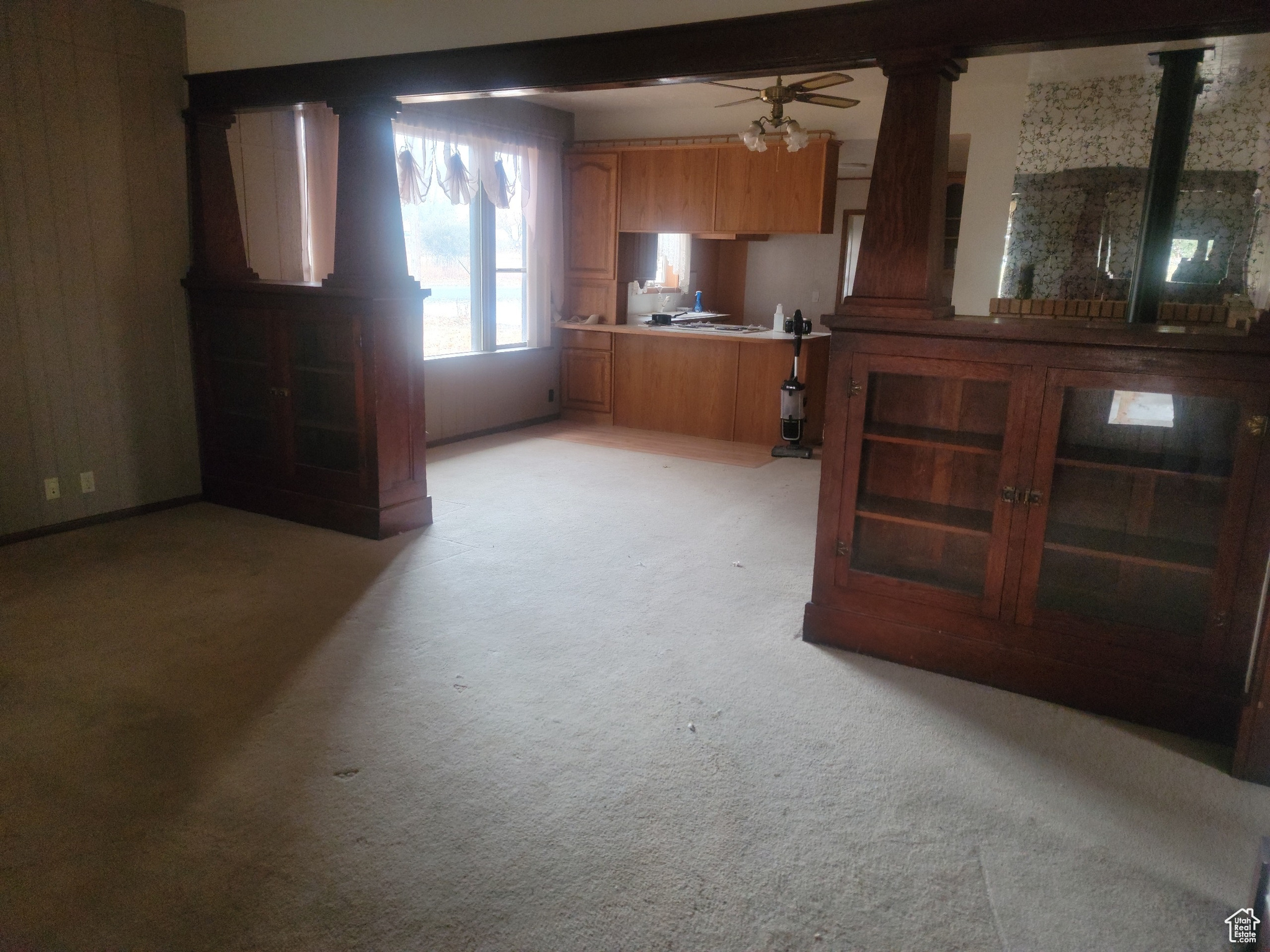 Interior space featuring ceiling fan, ornate columns, beam ceiling, and kitchen peninsula