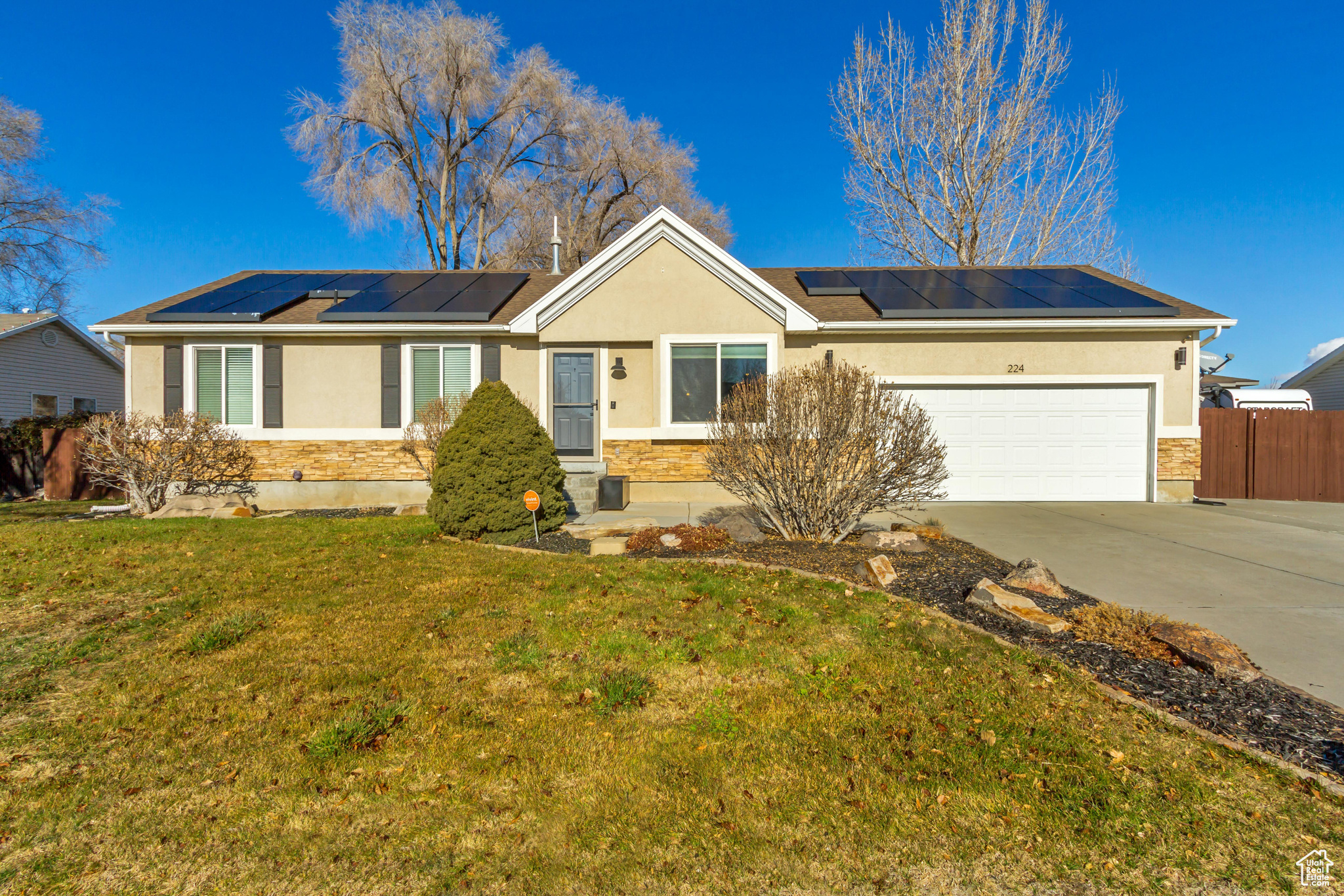 Ranch-style house featuring a garage, a front yard, and solar panels