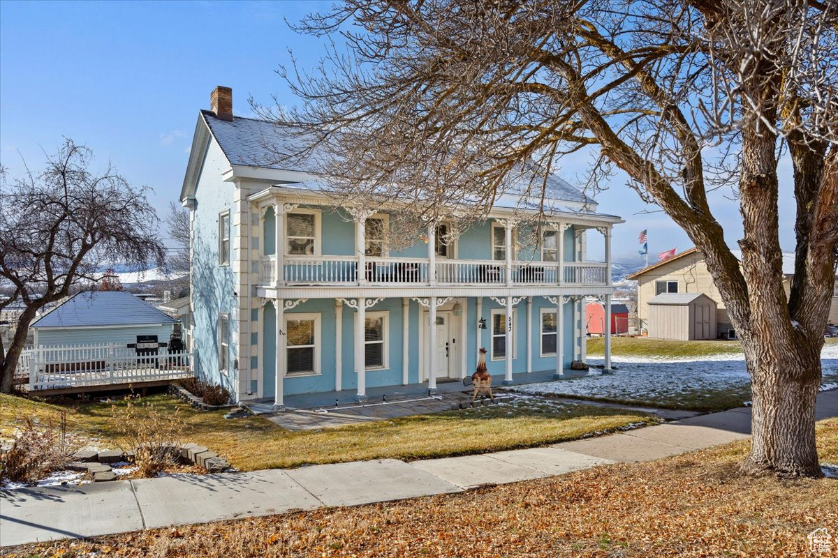 View of front of home with a balcony, a porch, and a storage unit