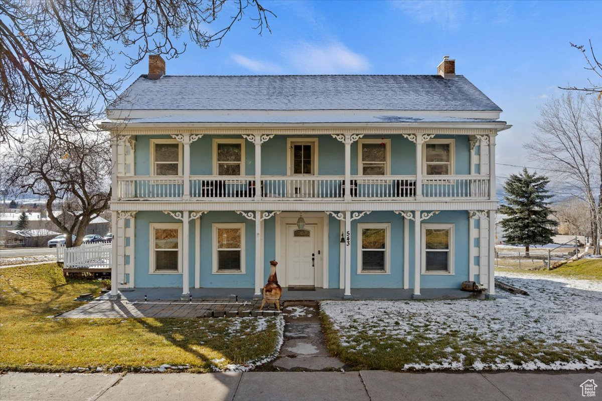 View of front of home with a balcony, covered porch, and a front yard