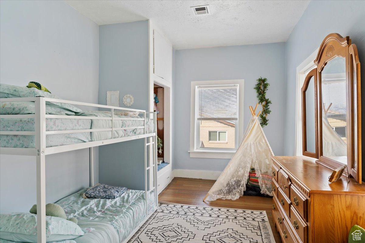 Bedroom with light hardwood / wood-style flooring and a textured ceiling