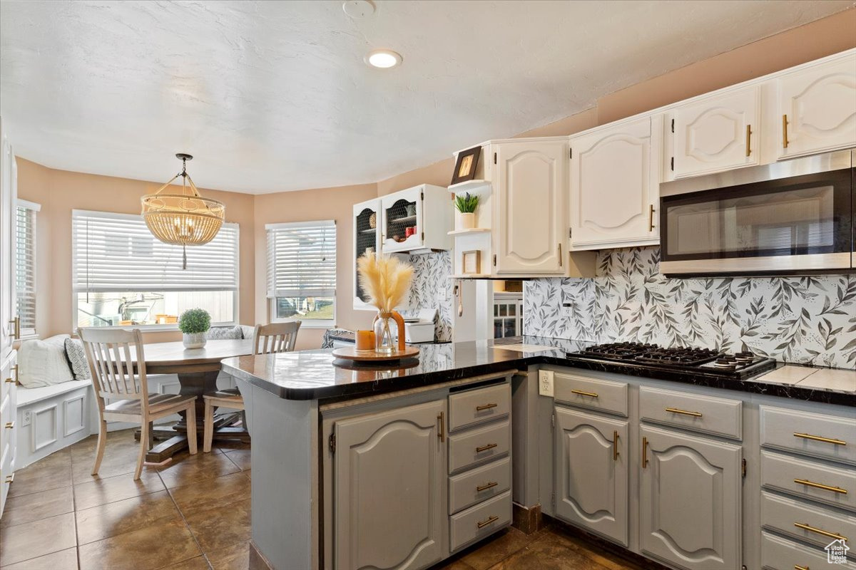 Kitchen with backsplash, gray cabinets, white cabinetry, kitchen peninsula, and stainless steel appliances