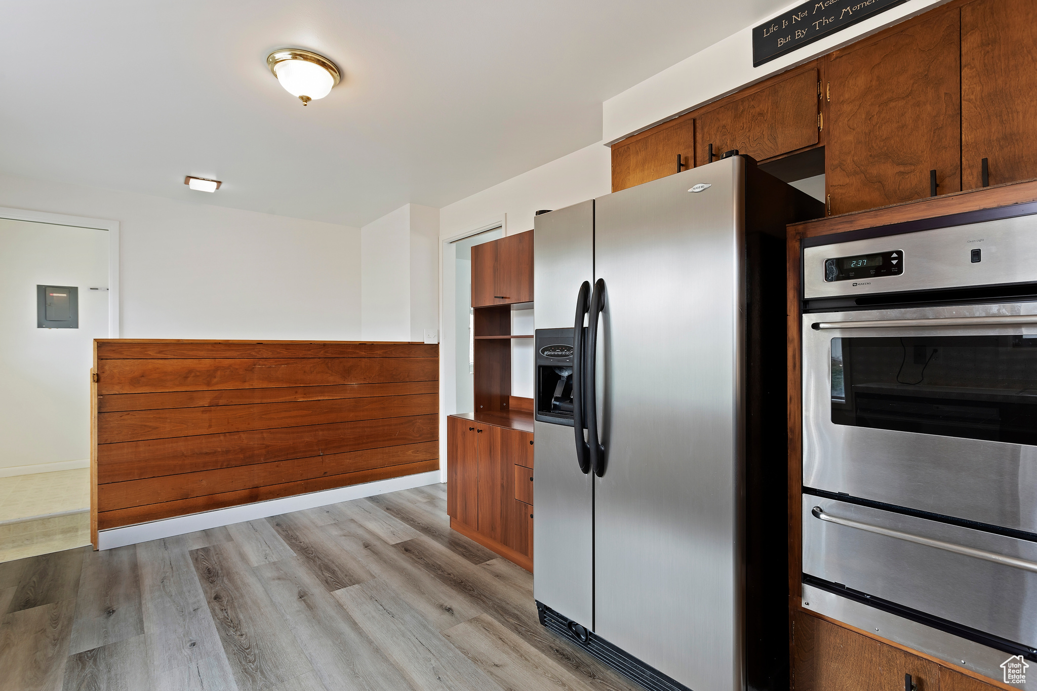 Kitchen featuring electric panel, light wood-type flooring, and appliances with stainless steel finishes