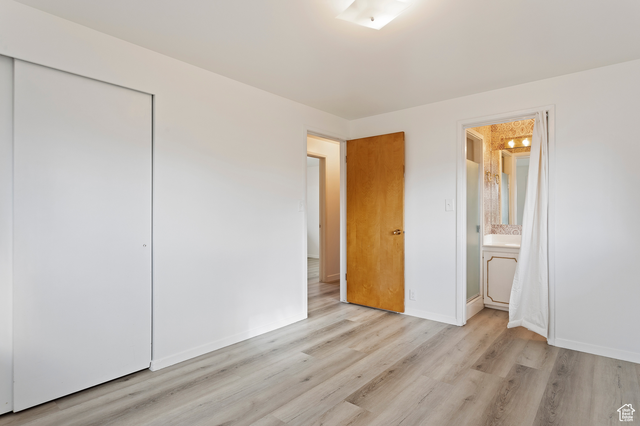 Unfurnished bedroom featuring ensuite bath, a closet, and light hardwood / wood-style flooring